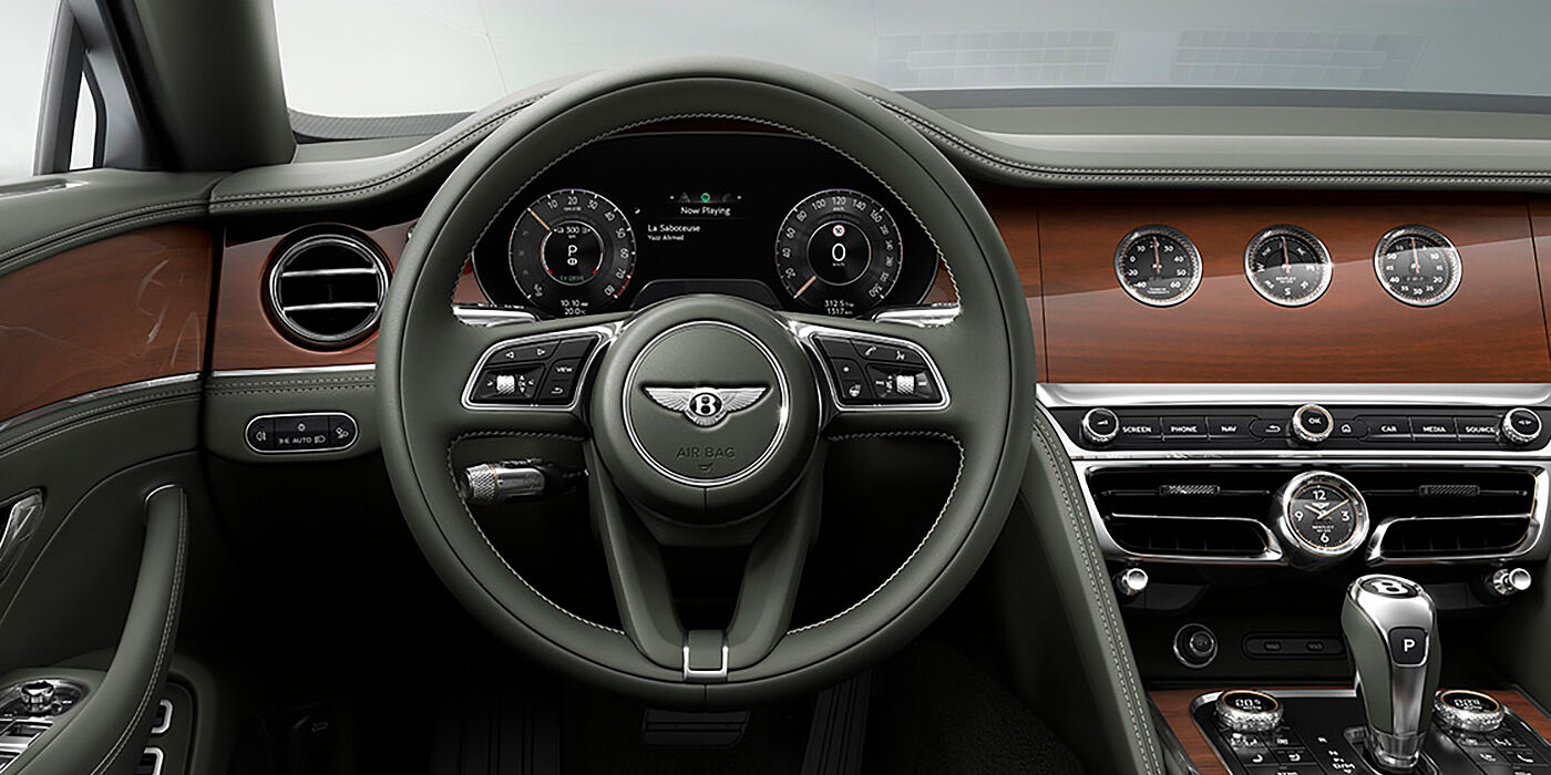 Bentley Kyiv New Bentley Flying Spur sedan front cabin in Cumbrian Green hide and Crown Cut walnut veneer showing steering wheel and Rotating Display with three clocks on face