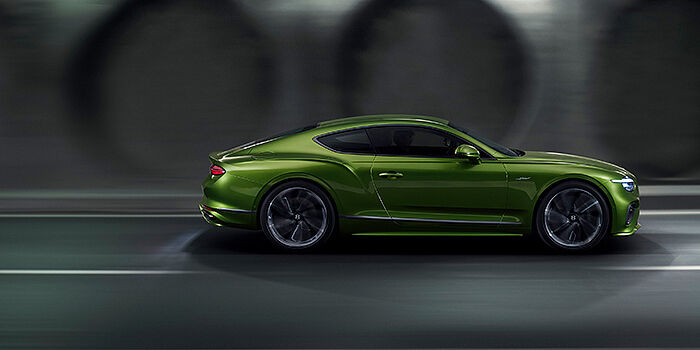  Bentley Kyiv Bentley Continental GT coupe in Tourmaline Green paint driving in profile on a dark road