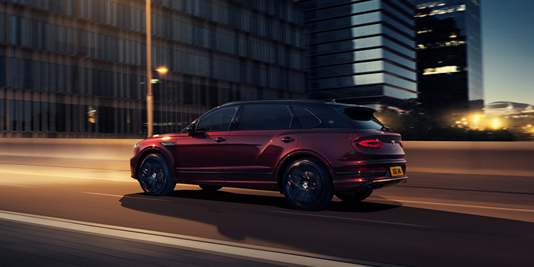 Bentley Kyiv Bentley Bentayga Extended Wheelbase Mulliner SUV in Cricket Ball red paint driving dynamically in city at night
