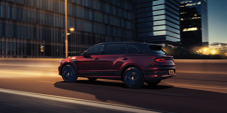 Bentley Kyiv Bentley Bentayga Extended Wheelbase Mulliner SUV in Cricket Ball red paint driving dynamically in city at night